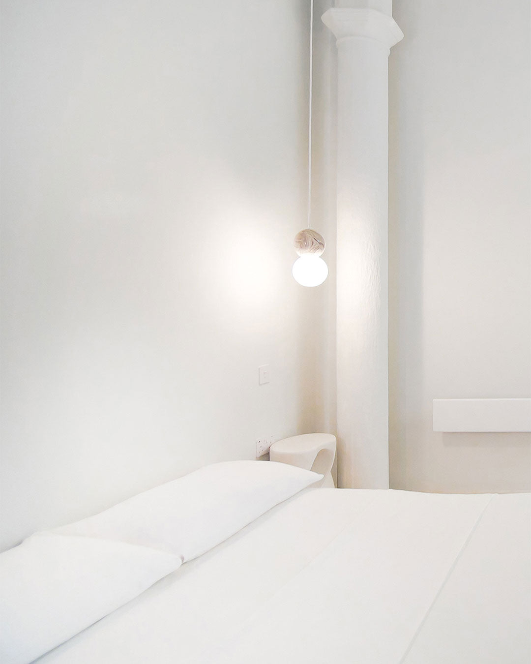 Minimalist bedroom with a bed and wall-mounted light fixture.