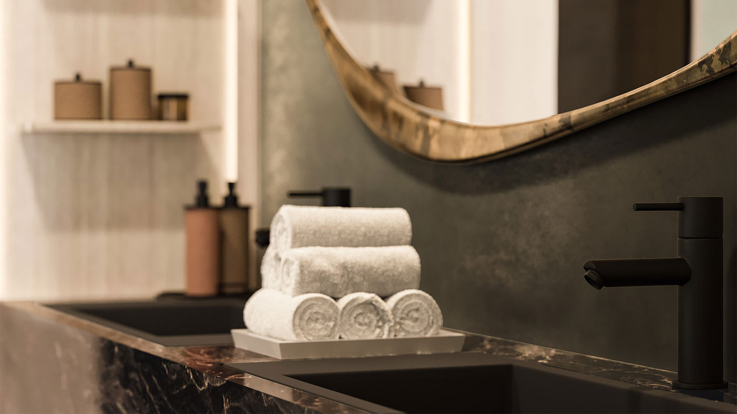 Stack of towels on a bathroom counter with a mirror and faucet in the background