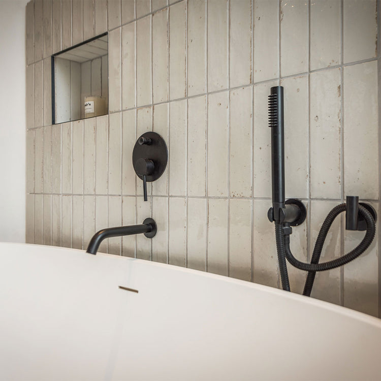 Bathroom setup with black fixtures on a tiled wall