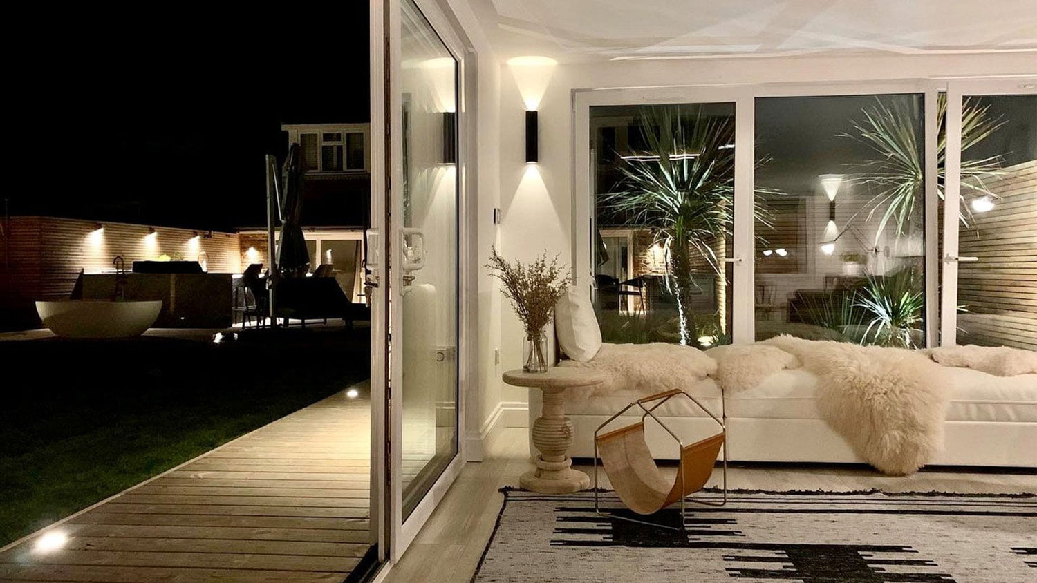 Modern outdoor living space with a sofa, chair, and decorative elements at night.