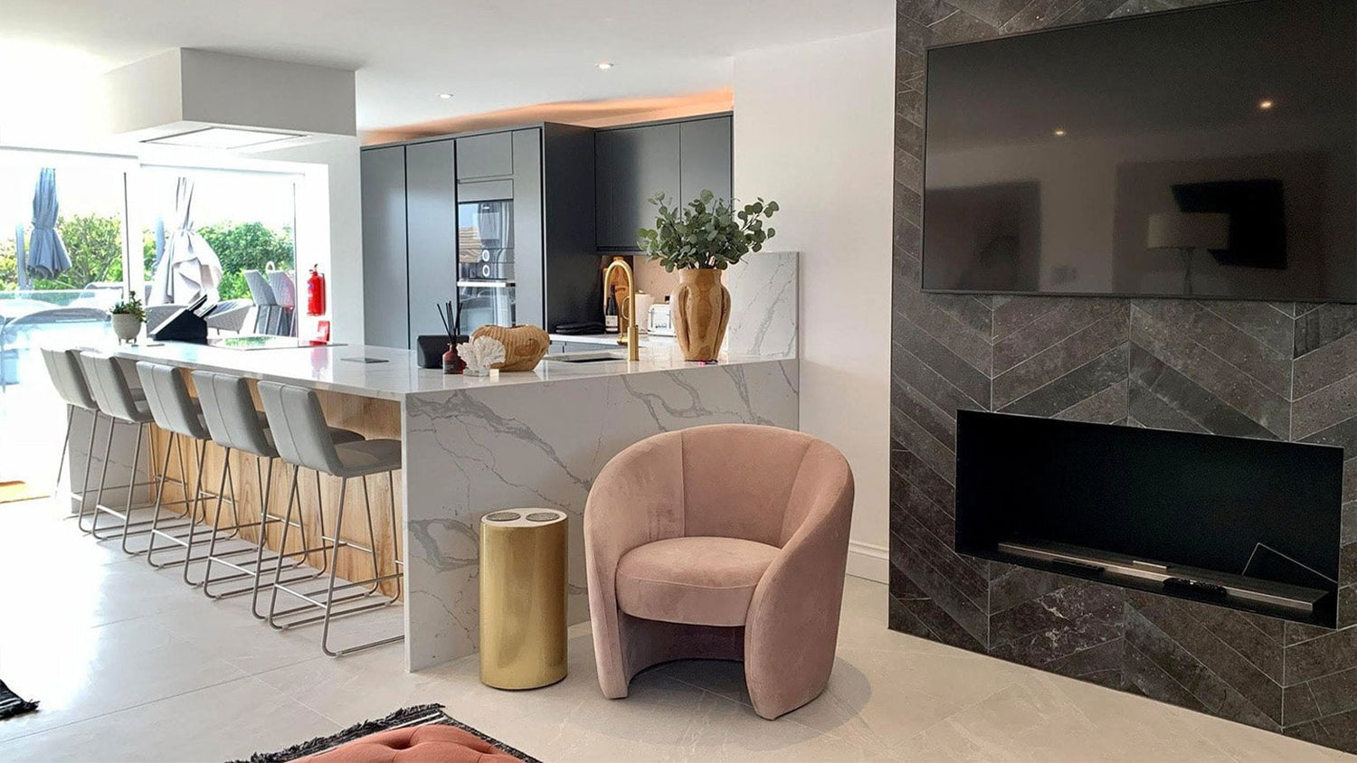 Modern living room with a pink armchair, marble counter, and television.