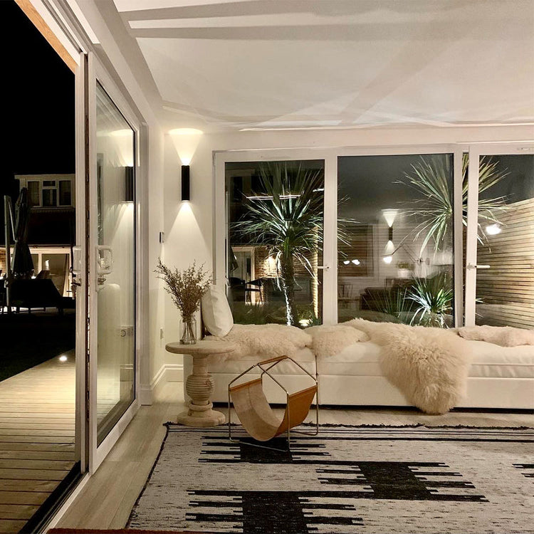 Modern living room with a white sofa, decorative rug, and large windows.