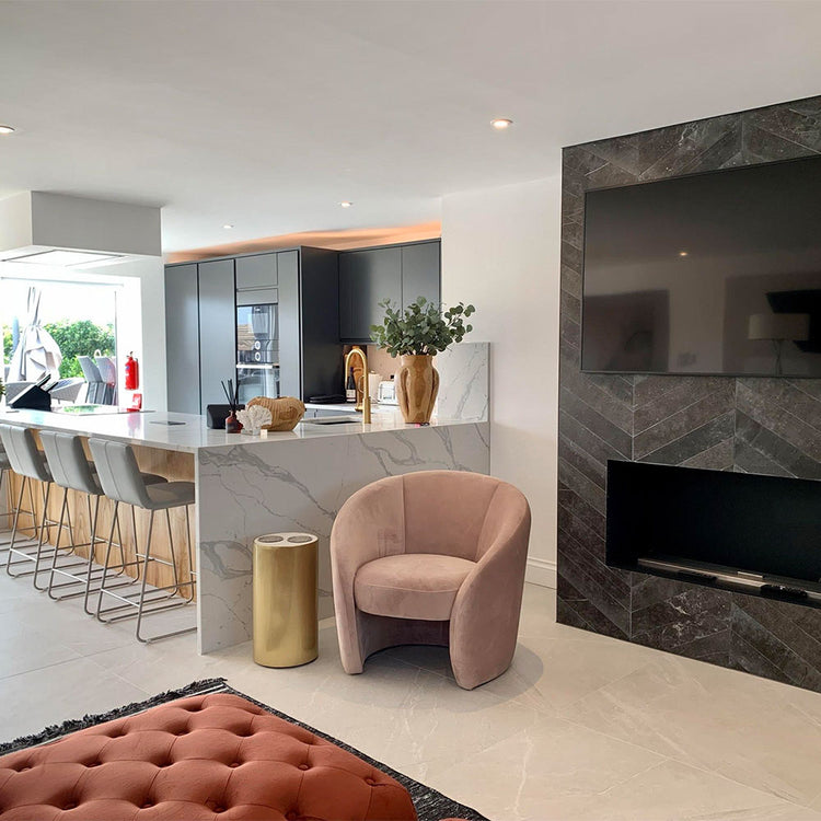 Modern living room with a pink armchair, marble counter, and fireplace.