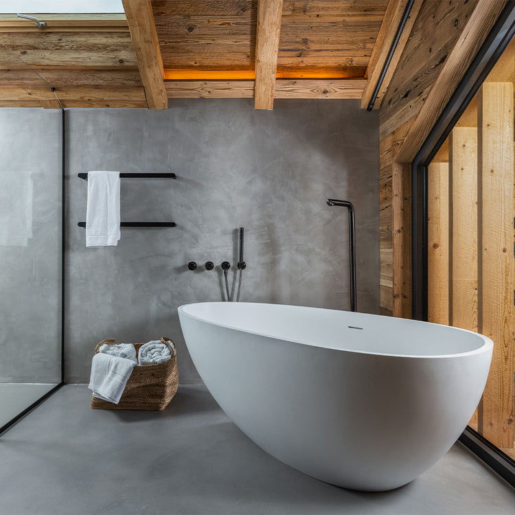 Modern bathroom with a freestanding bathtub, wooden beams, and concrete walls.
