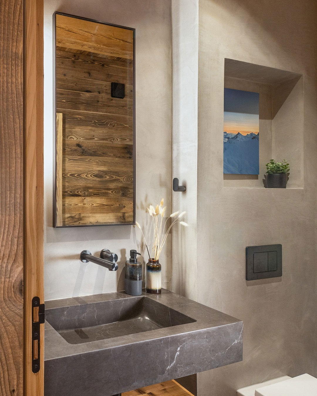 Bathroom interior with a wooden-framed mirror, sink, and wall art.