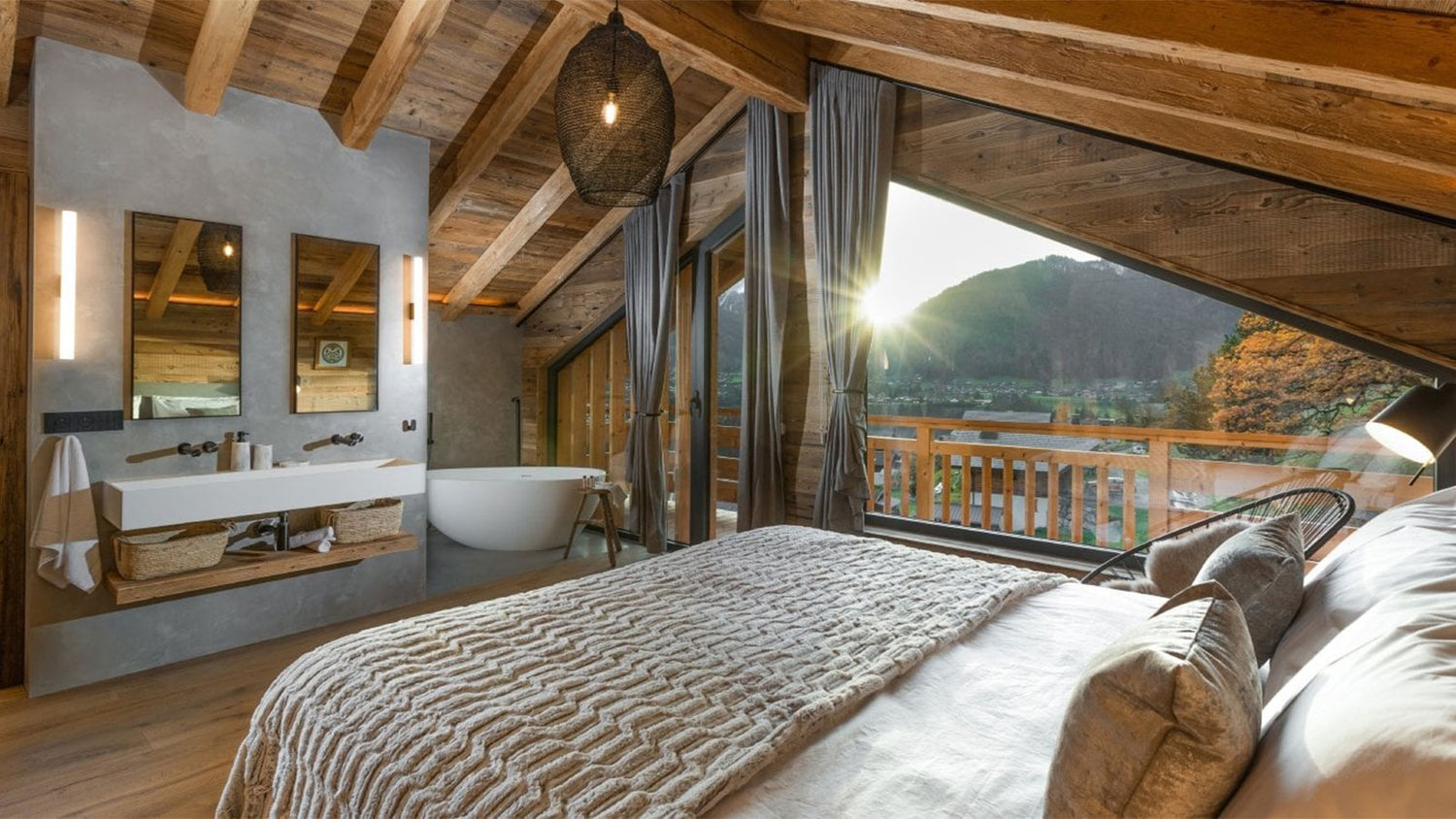 Luxury bedroom with wooden beams, a bed, and a bathroom with a view of mountains.