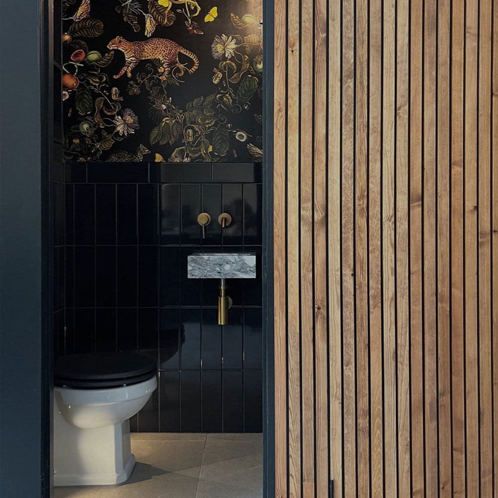 Bathroom with black tiled wall, white toilet, and wooden slat wall.