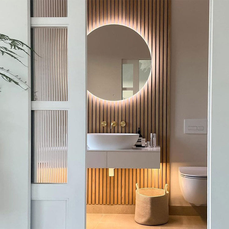 Modern bathroom interior with a round mirror, sink, and wooden paneling.