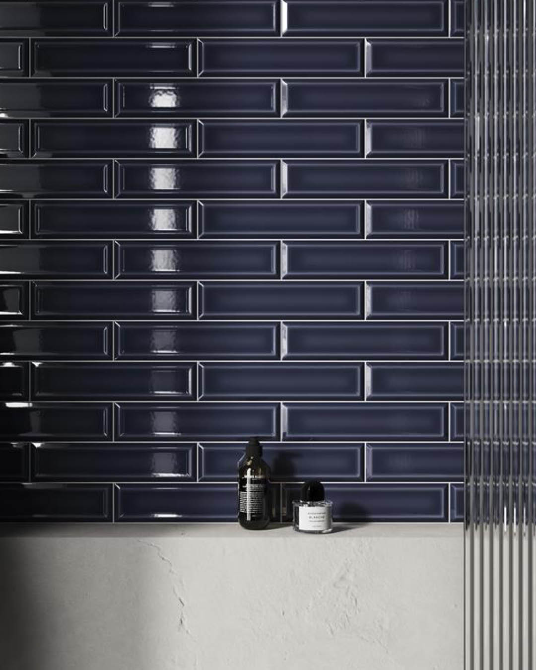 Navy blue tiled wall with two bottles on a white surface.