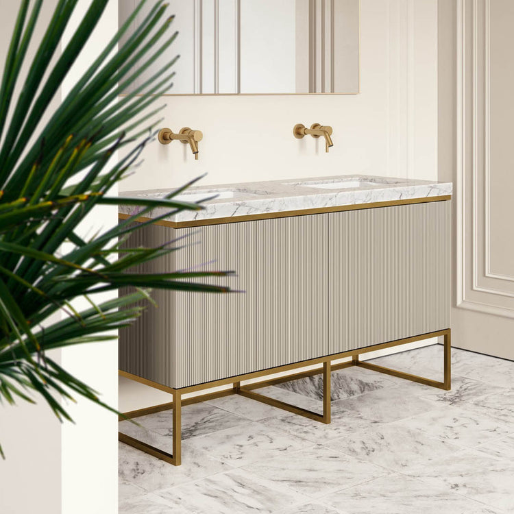 Bathroom vanity with marble countertop and gold fixtures, featuring a plant in the foreground.