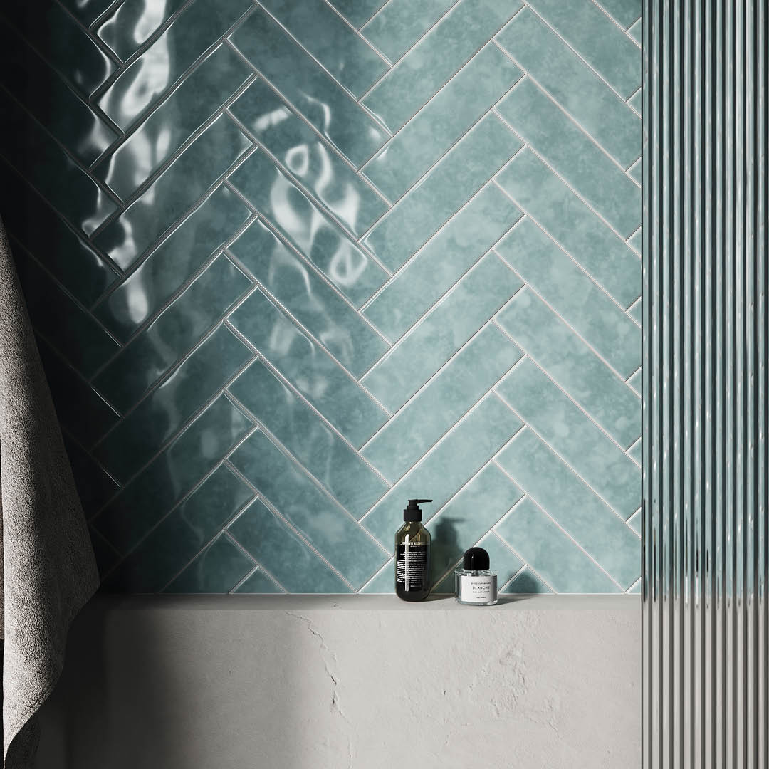 Teal herringbone tiles on a wall with bathroom products below.