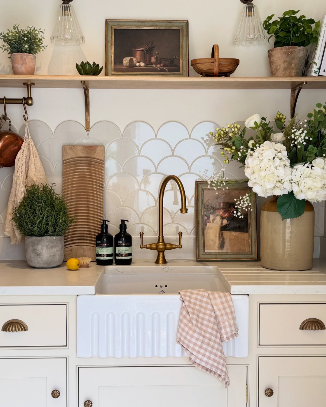 Kitchen with white sink, gold faucet, and decorative elements.