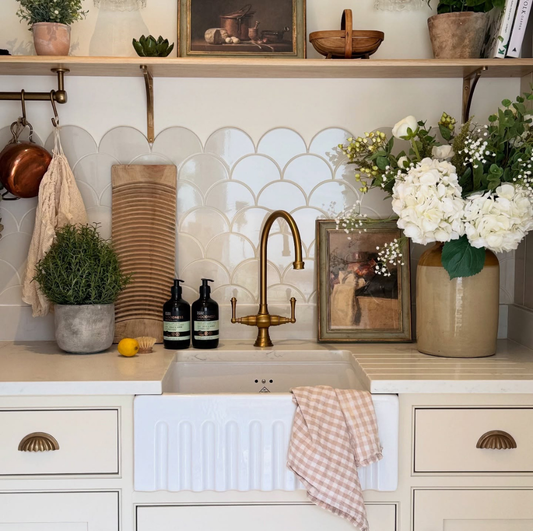 Kitchen with a sink, shelves with decor items, and a vase of flowers.