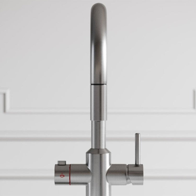 Stainless steel kitchen faucet with control handle on a white tiled wall background