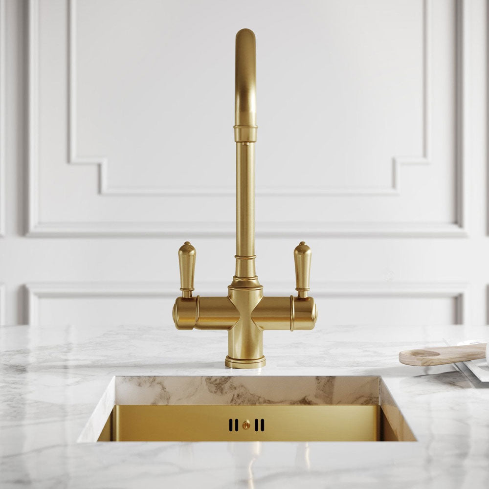 Gold kitchen faucet on a marble countertop with a white paneled wall background
