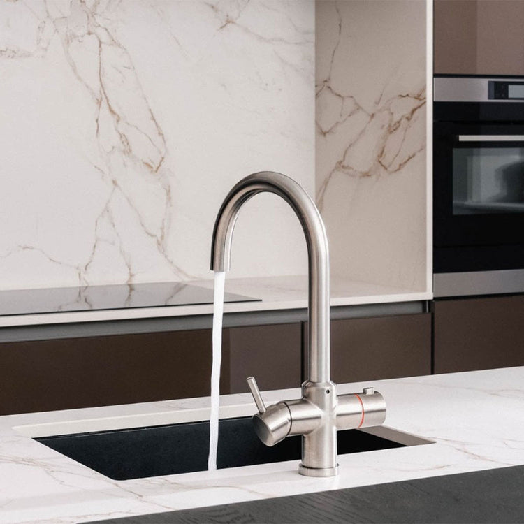 Modern kitchen faucet with running water in a marble and black countertop setting