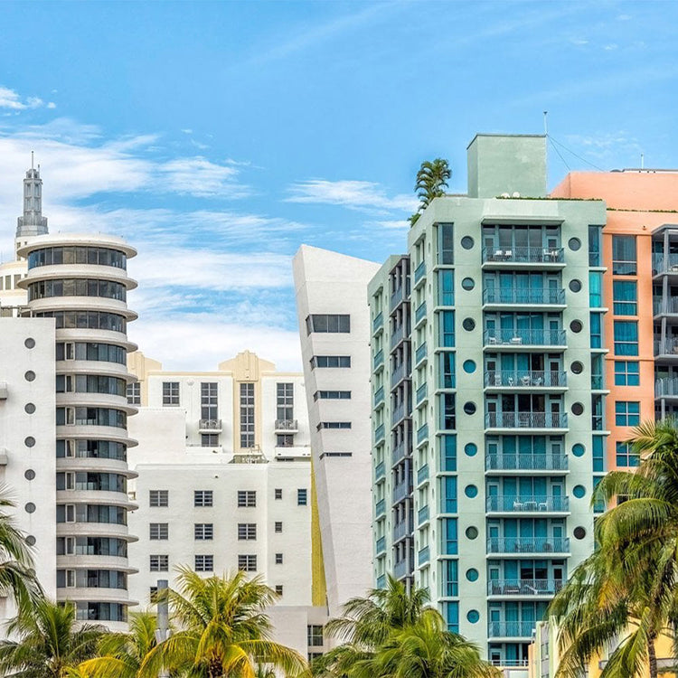 Tall apartment buildings with palm trees against a blue sky