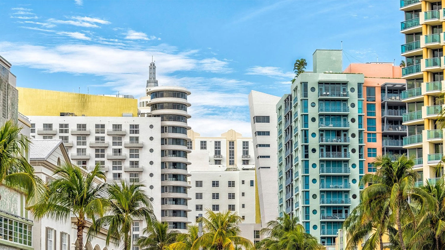 Urban scene with tall buildings and palm trees under a blue sky.