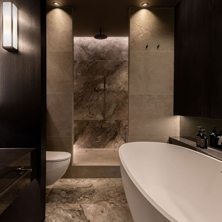 Modern bathroom with marble tiles, a freestanding bathtub, and a toilet.