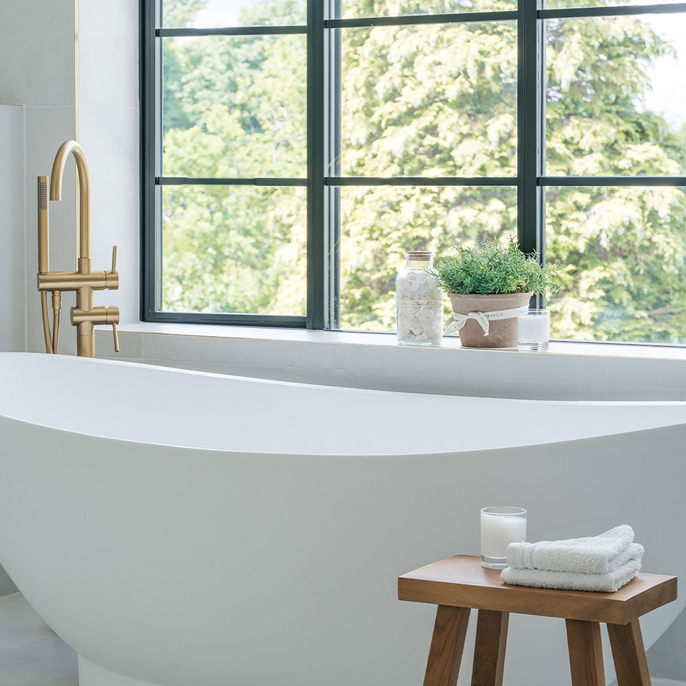 Modern bathroom with a freestanding bathtub, wooden stool, and large window.
