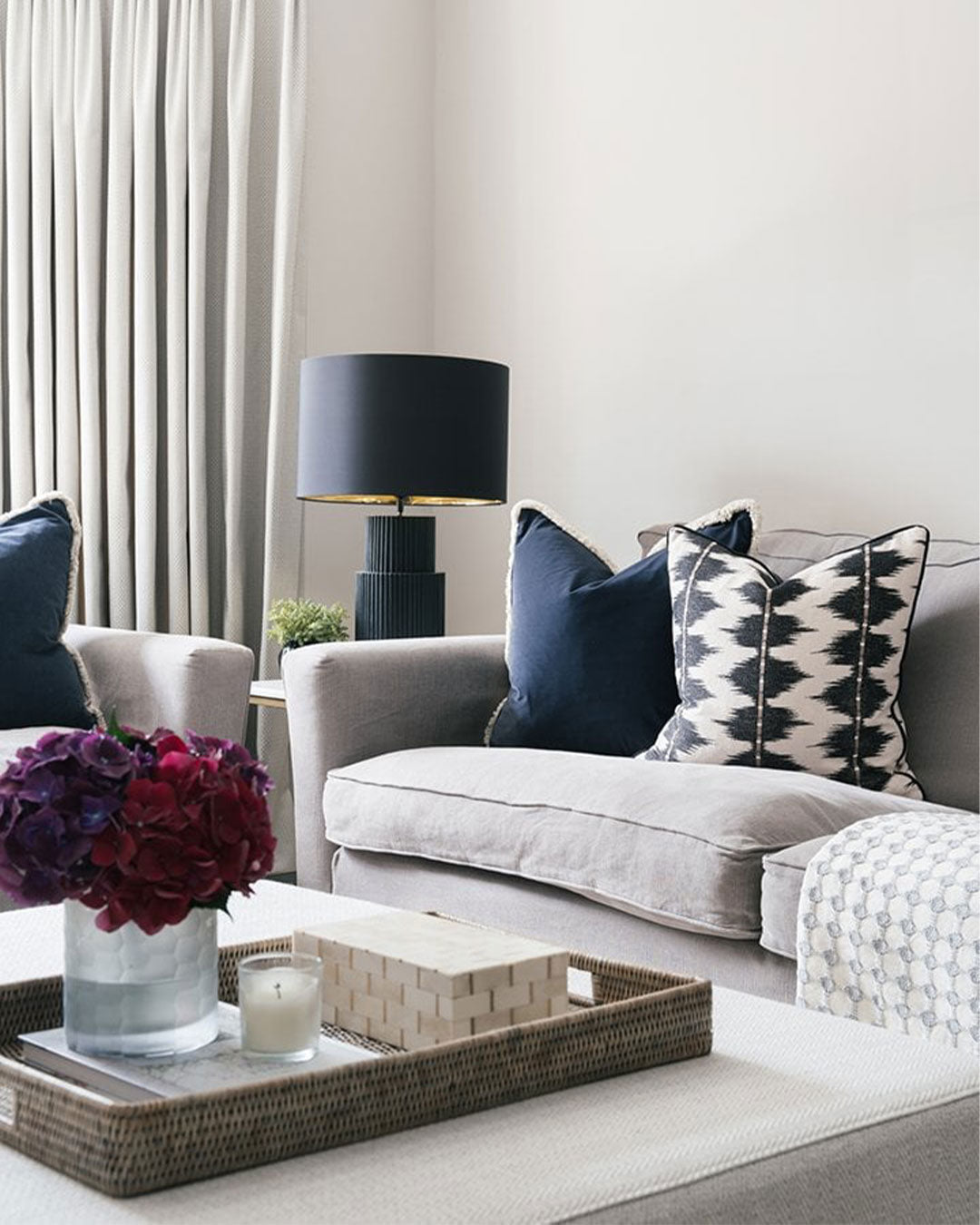Modern living room with a grey sofa, decorative pillows, and a lamp.