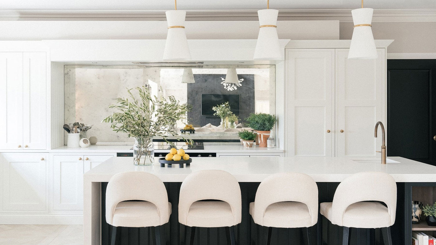 Modern kitchen with white island, chairs, and decorative elements.