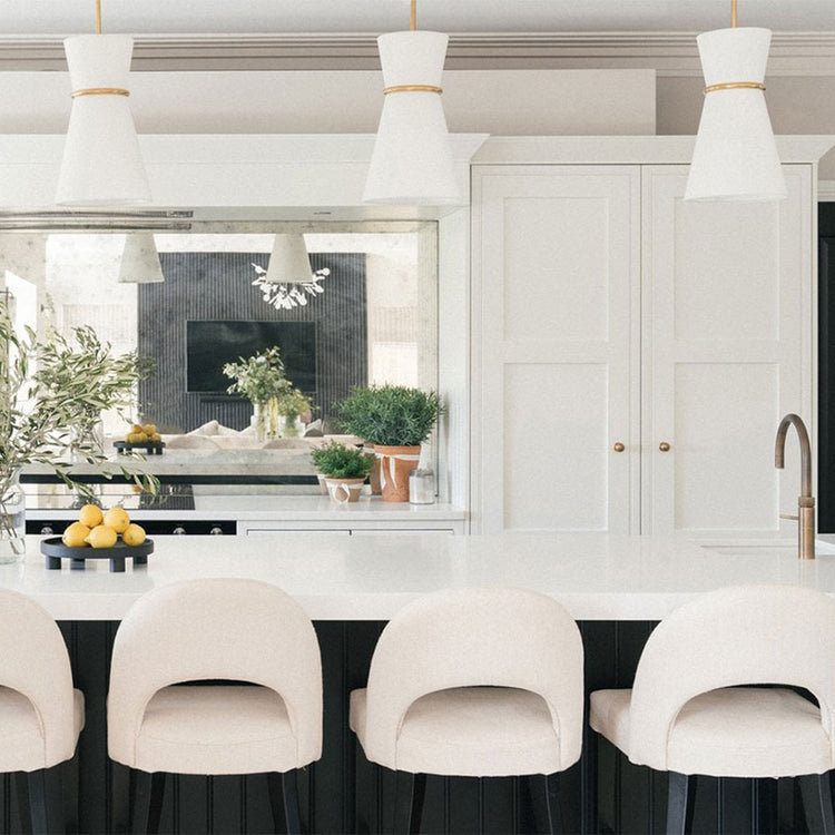 Modern kitchen with white island, stools, and pendant lights.