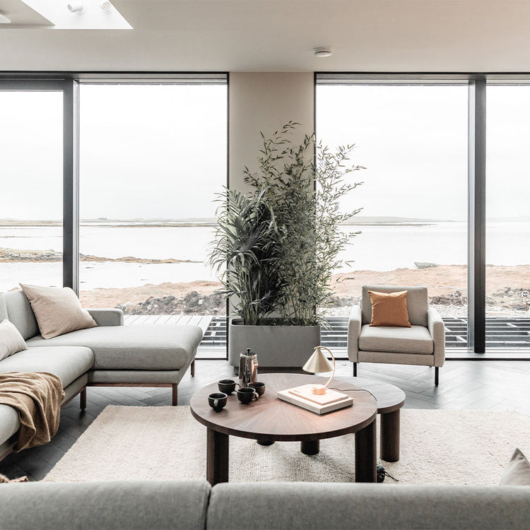 Modern living room with large windows, gray sofa, and wooden coffee table.