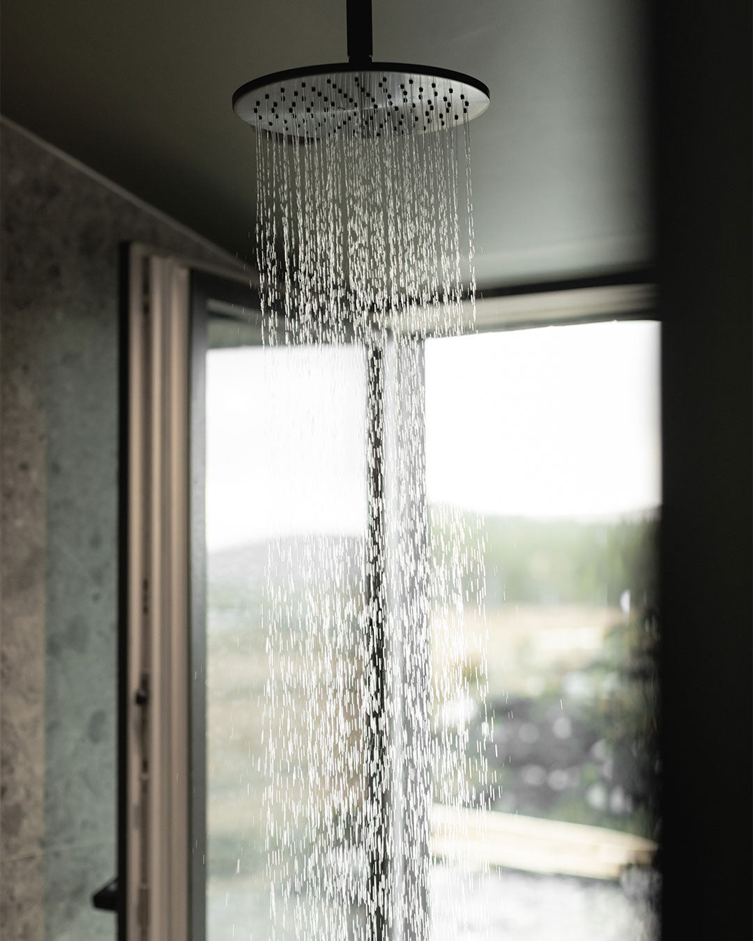 Shower head with water droplets in a bathroom setting