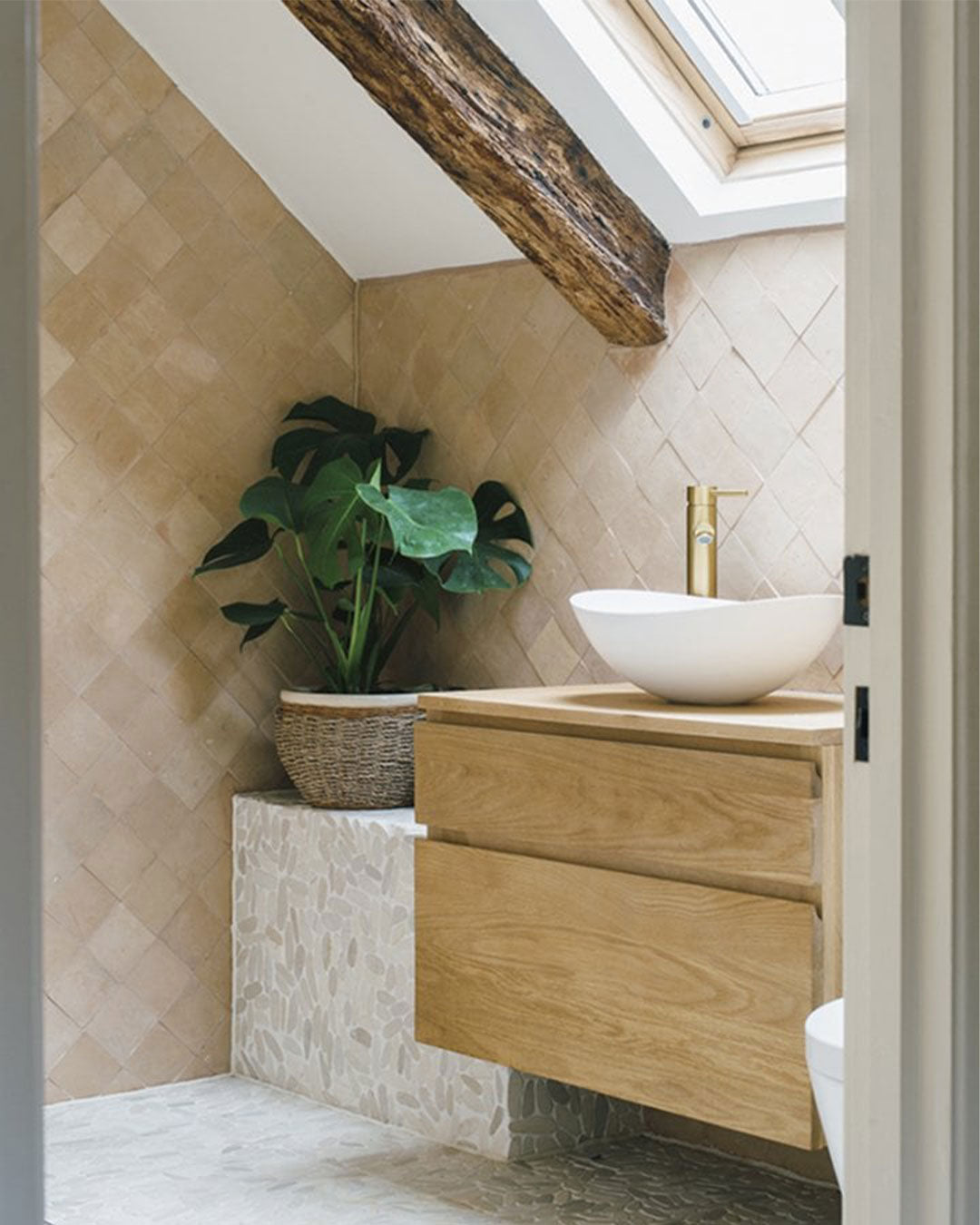 Bathroom with wooden vanity, white sink, and plant