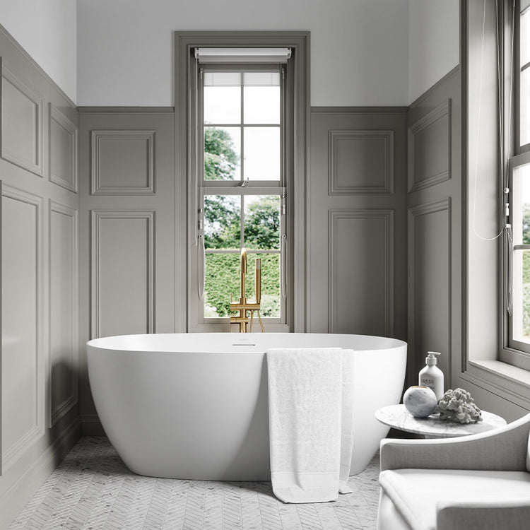Modern bathroom with a freestanding bathtub, gray walls, and a window view.