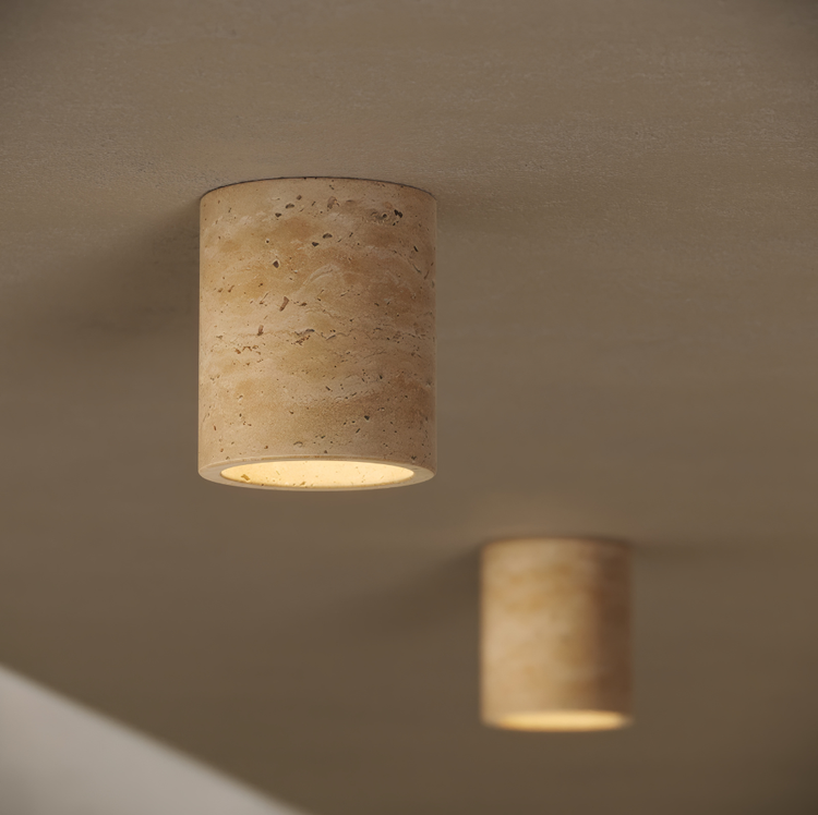 Two cylindrical stone lights on a beige wall.