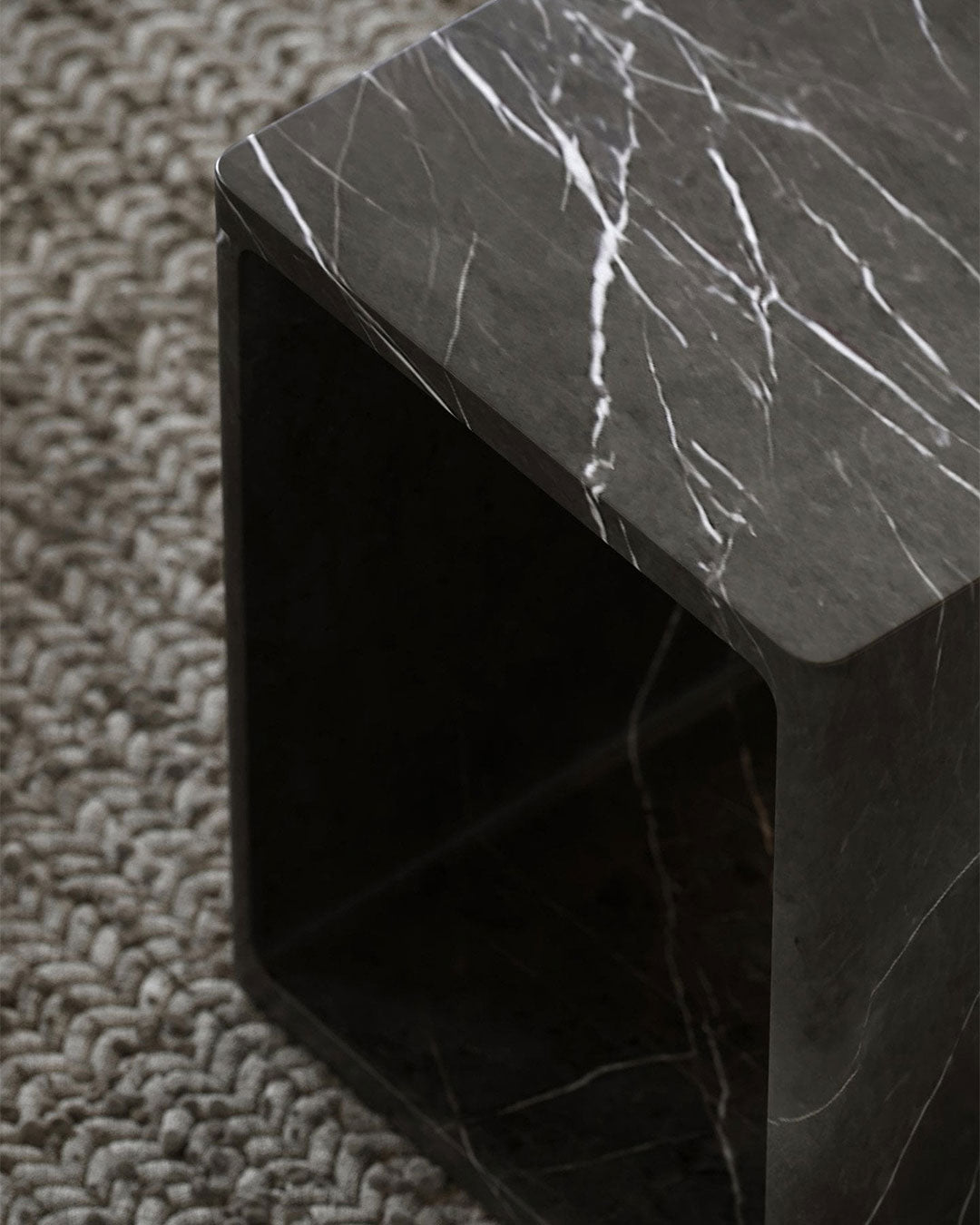 Dark marble side table on a textured carpet