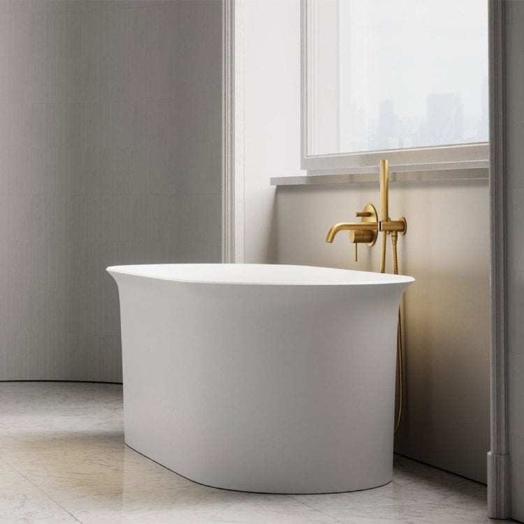 Modern white freestanding bathtub with gold faucet in a bathroom setting