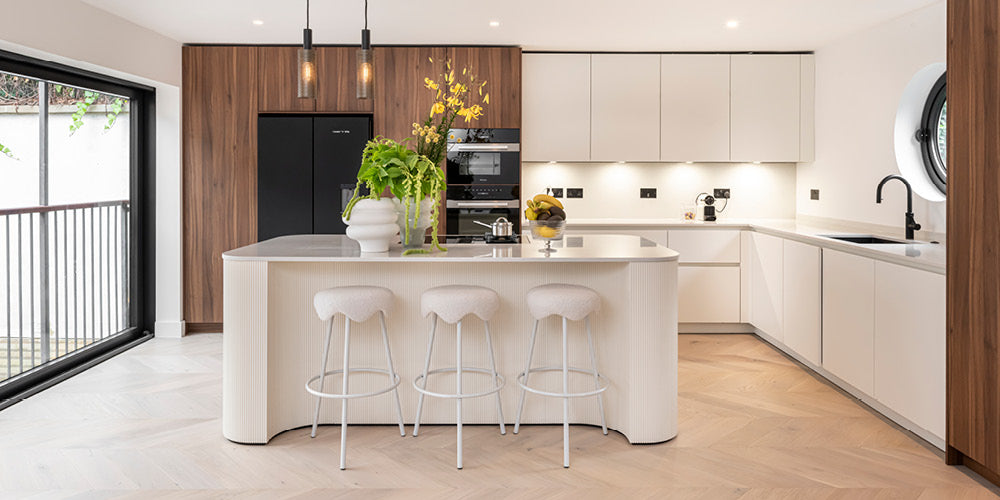 Modern kitchen with white island, bar stools, and wooden cabinets.