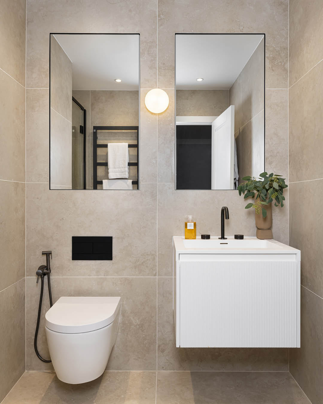Modern bathroom with tiled walls, a white toilet, and a vanity with a mirror.