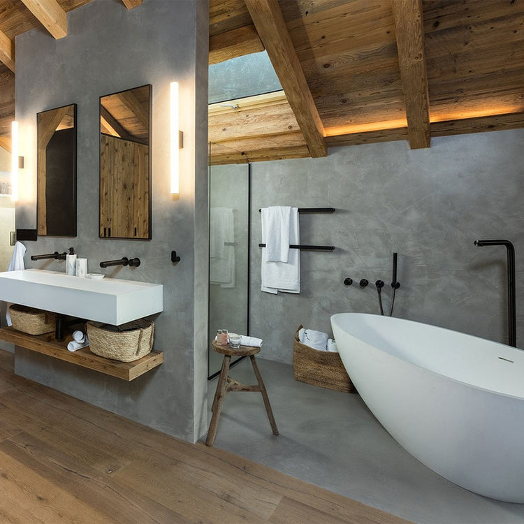 Modern bathroom with wooden beams, white freestanding bathtub, and concrete walls.
