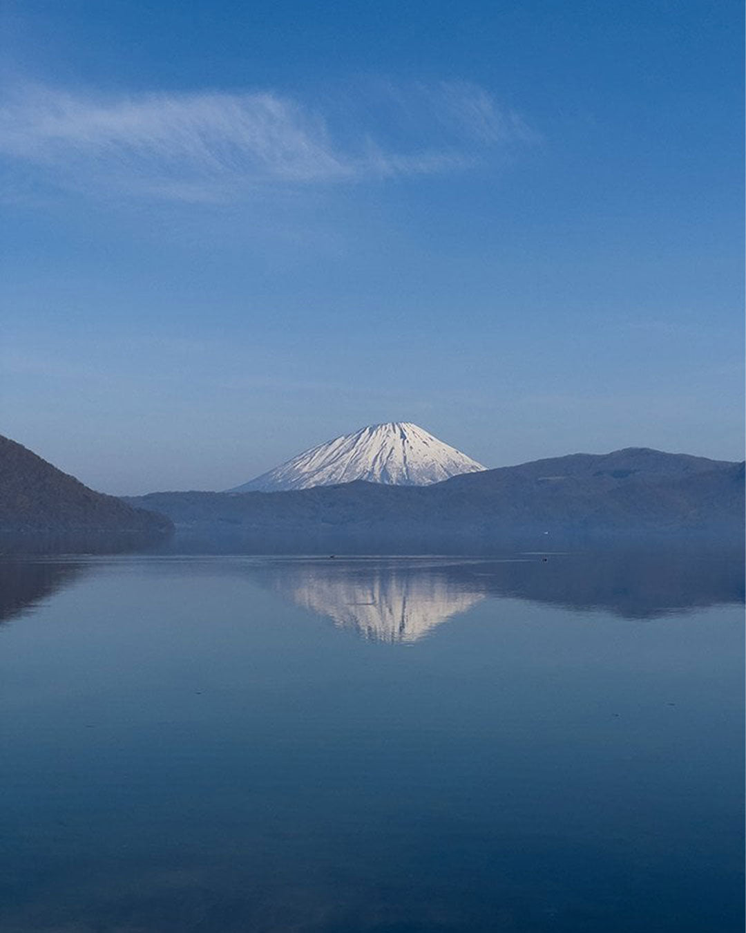 Mountain reflected in a calm lake under a clear blue sky