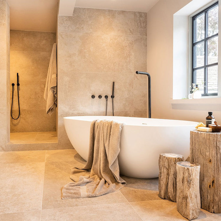 Modern bathroom with a freestanding bathtub, towel, and wooden stools.