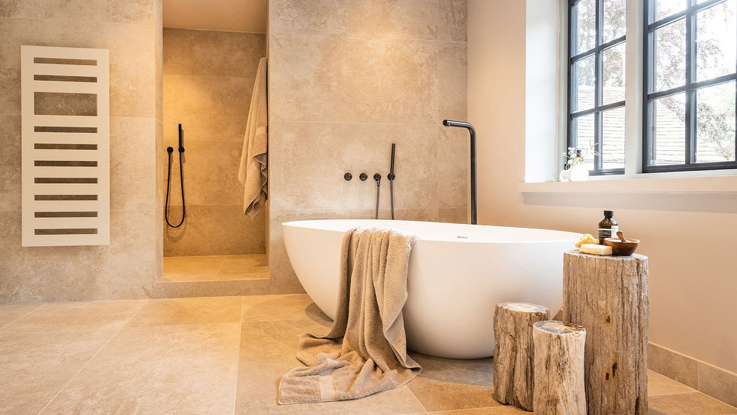 Modern bathroom with a freestanding bathtub, towel, and wooden stool.