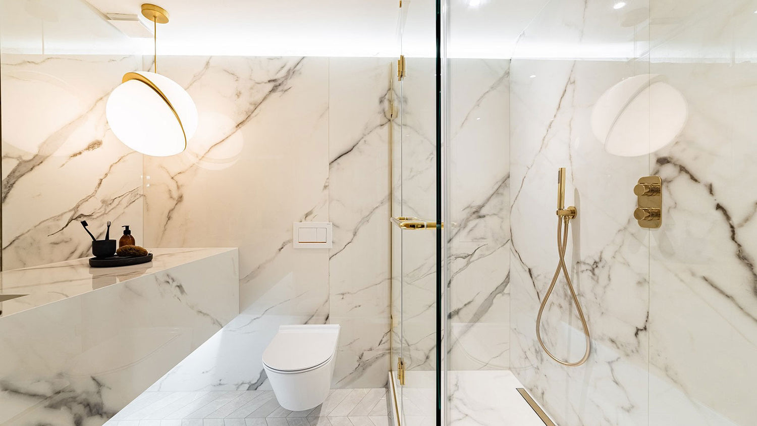 Modern bathroom with marble walls, a toilet, and shower area.