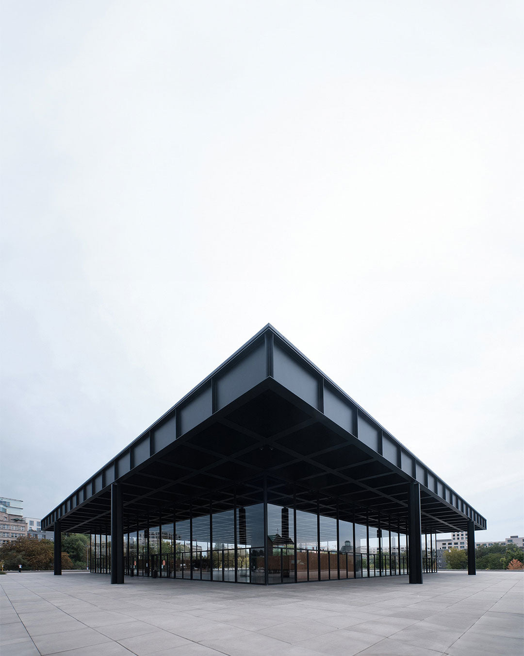 Modern architectural building with a flat roof and large glass windows on a cloudy day.
