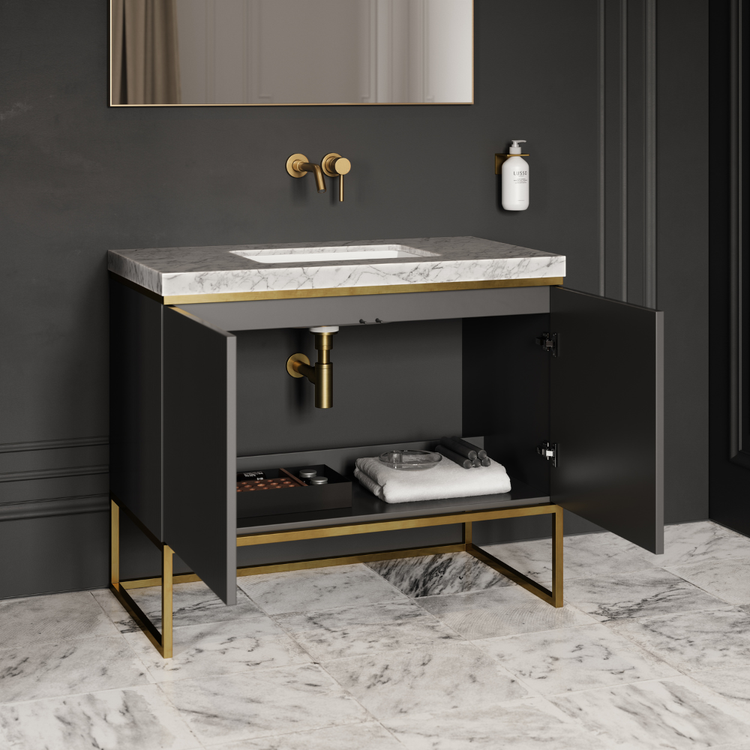 Bathroom vanity with marble countertop and gold fixtures against a dark grey wall.