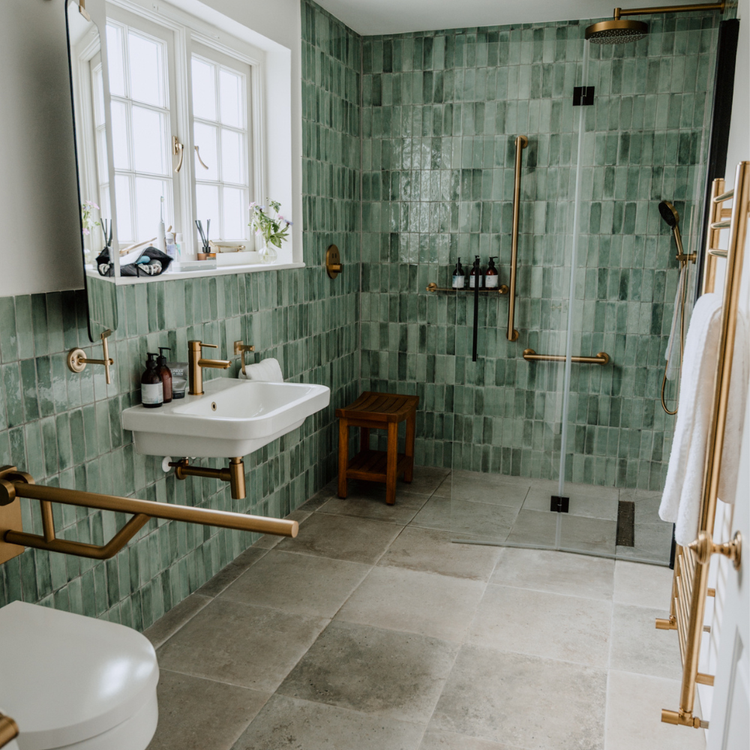 Modern bathroom with green tiled walls, gold fixtures, and a shower area.