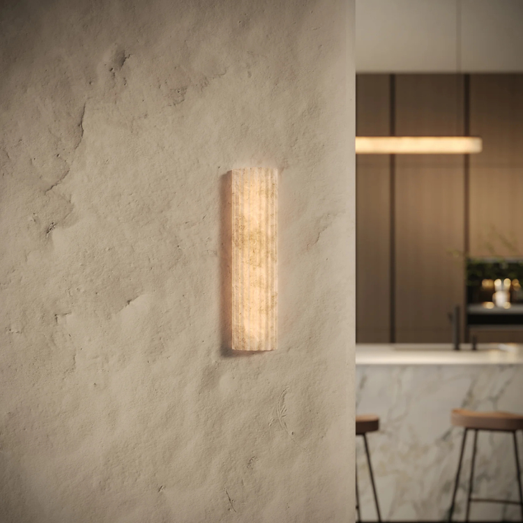Wall-mounted light fixture on a textured wall with a blurred kitchen background