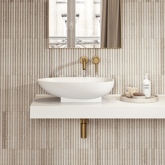 Bathroom with a white sink, gold fixtures, and a mirror on a tiled wall.