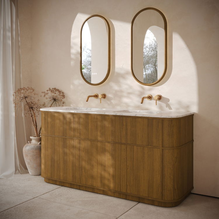 Bathroom vanity with wooden finish and two oval mirrors on a beige wall.