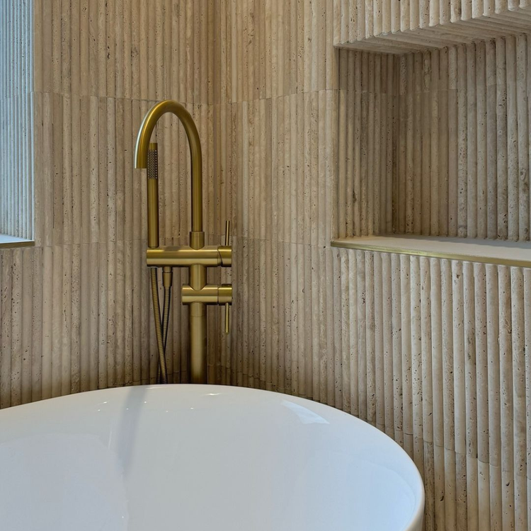 Gold faucet over a white bathtub in a bathroom with wooden walls.