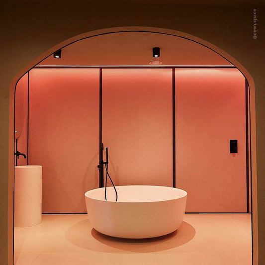 Modern bathroom with a white bathtub in a pink-orange room.