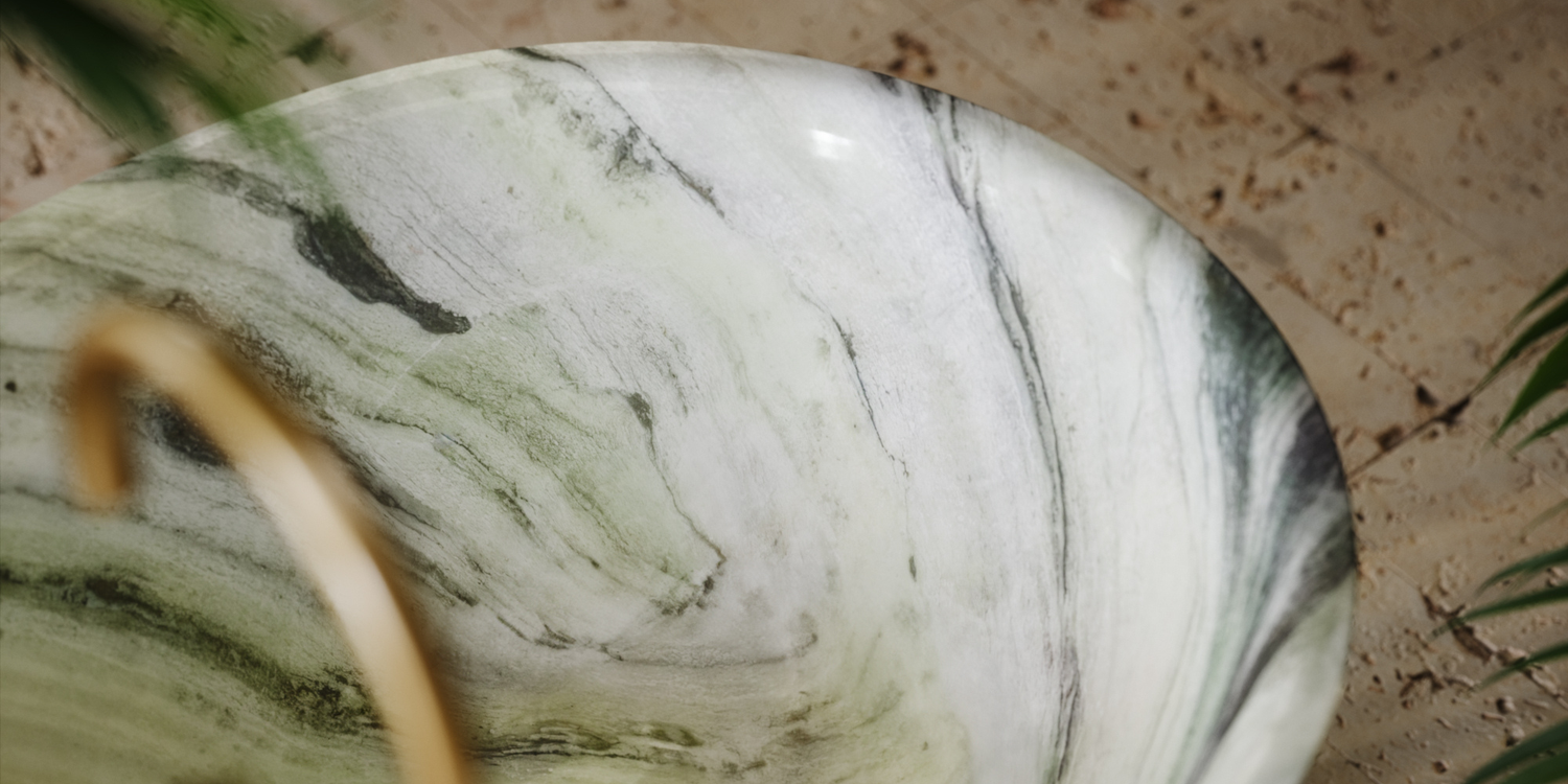 Close-up of a marbled stone bath with green and white patterns on a natural background